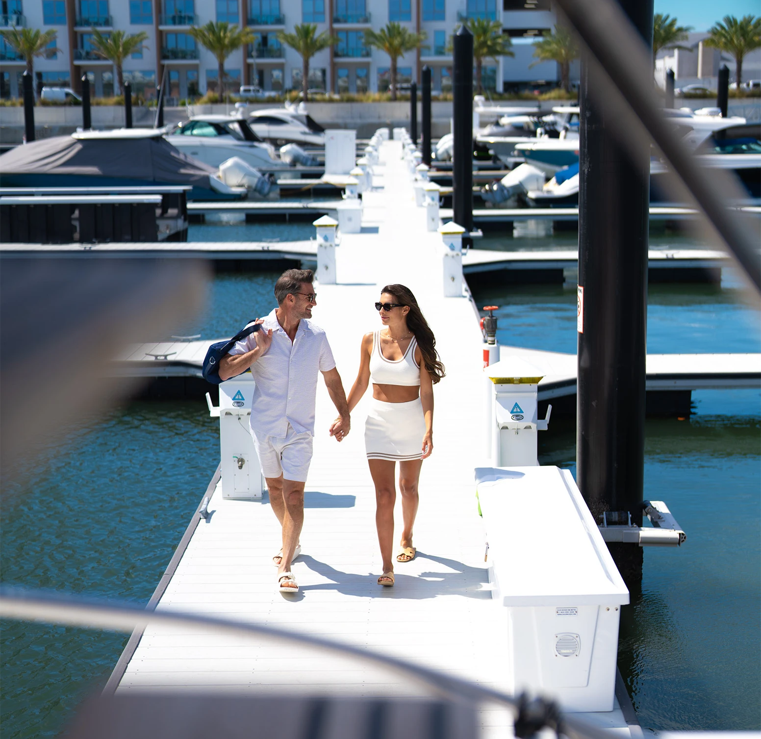 Couple walking on a dock at Marina Pointe, showcasing new construction waterfront condos for sale in Tampa's Westshore Marina District with modern architecture, luxury interiors, and deepwater marina access, surrounded by resort-style amenities.