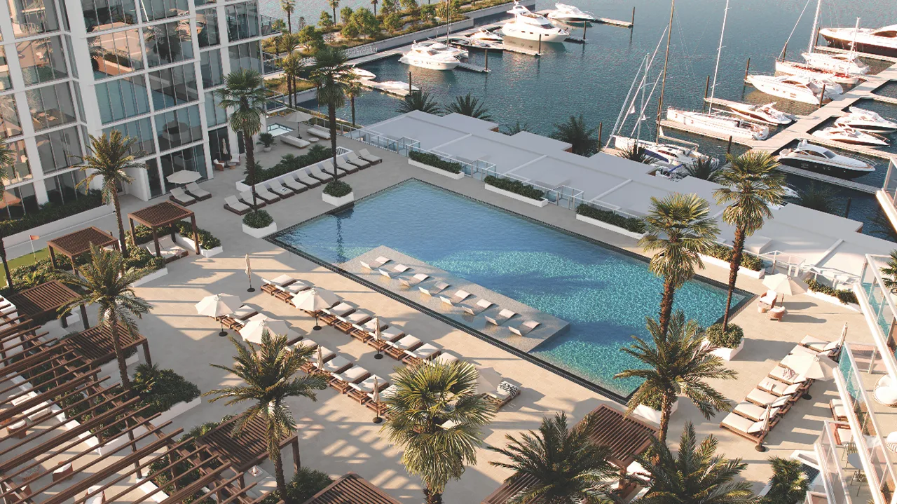 Aerial view of a pool deck with lounge chairs and nearby marina.