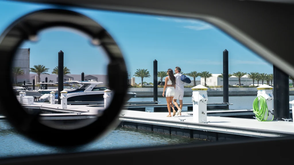 Couple walking on marina dock beside yachts and waterfront condos